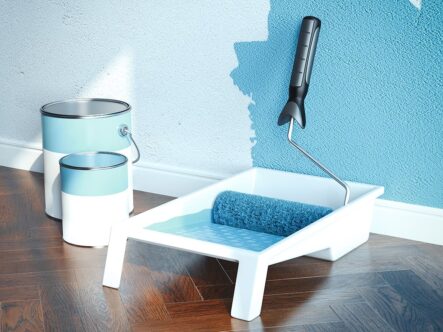 paint roller and two paint boxes in picture.